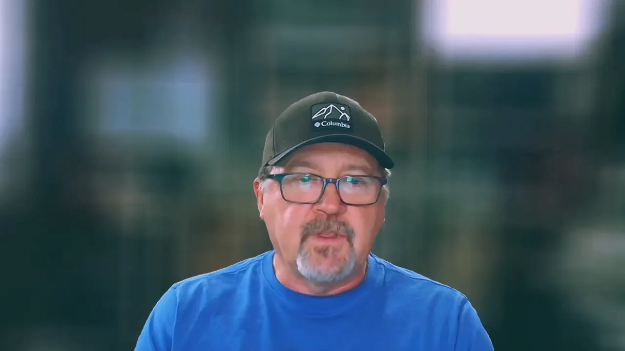 Guest participant wearing a cap and glasses speaking on a video call with blurred background